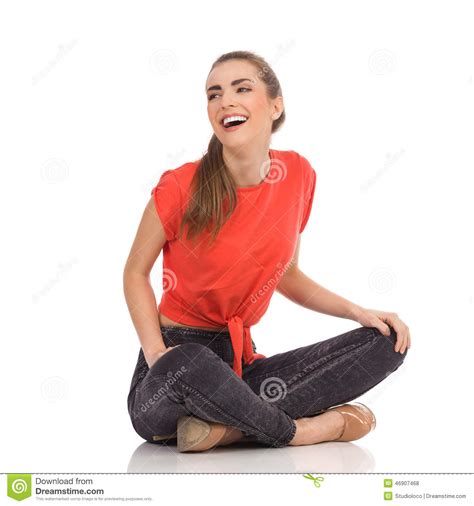 laughing girl sitting on the floor with legs crossed stock
