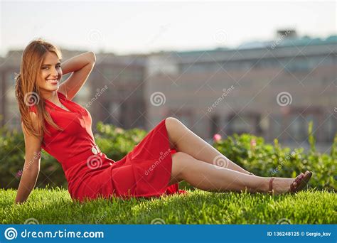 Jonge Mooie Glimlachende Vrouw In Rode Kledingszitting Op Een Groene