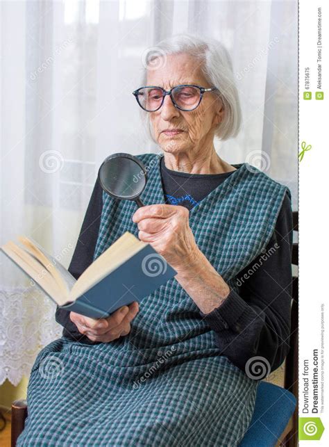 grandma reading a book through magnifying glass stock image image of