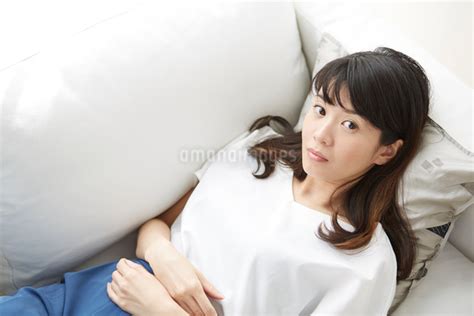 ソファで仰向けに寝るカメラ目線の女性の写真素材 [fyi01464488] ストックフォトのamanaimages plus