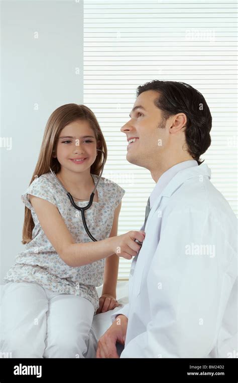 girl listening to the heartbeat of a doctor with a stethoscope stock