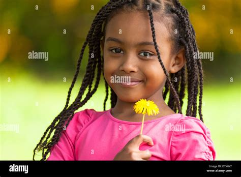Outdoor Portrait Of A Cute Young Black Girl Holding A Dandelion Flower