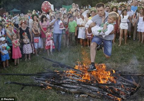 a very hot hop ukranian revellers leap over campfire to