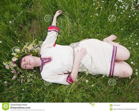 barefoot teen girl in a chaplet lying from meadow stock