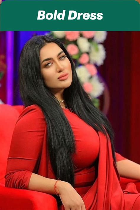 a woman sitting in a red chair with long black hair and wearing a red dress