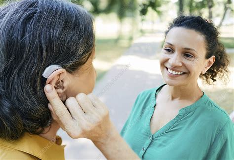 Woman Adjusting Hearing Aid Stock Image F034 9101 Science Photo