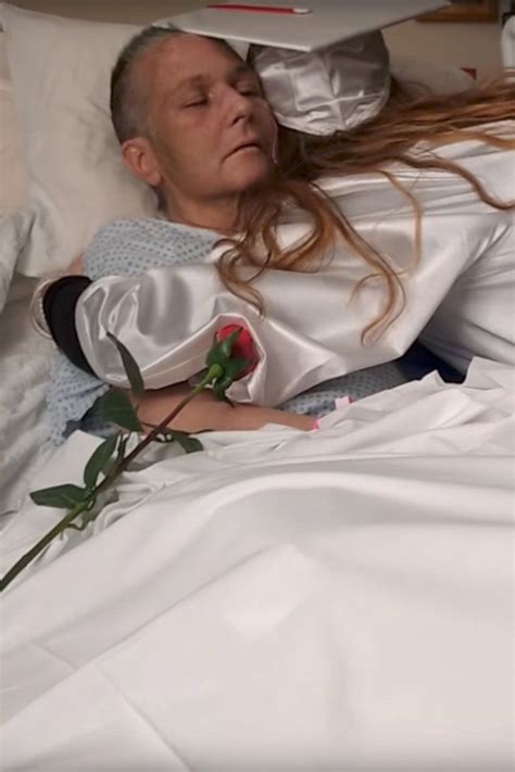 A Woman Laying In Bed With Her Eyes Closed And Holding A Rose Up To Her Ear