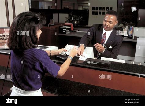 austin texas usa black male bank teller serves hispanic customer  bank lobby teller window