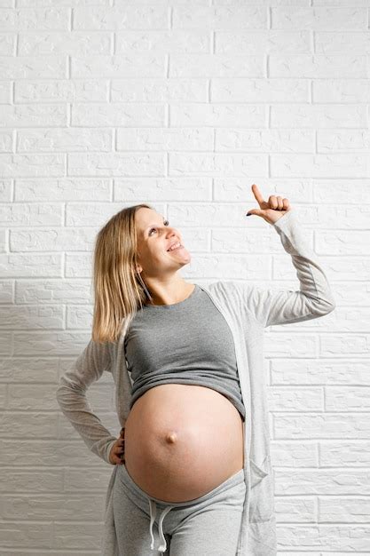 het zwangere vrouw stellen voor een witte muur premium foto