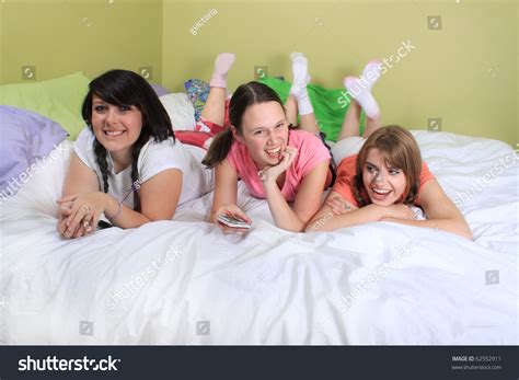 Group Of Three Teenage Girls Hanging Out On A Bed In Their Pajamas