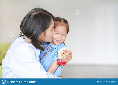 portrait of asian mom kissing and hugging her daughter on