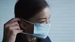 Woman putting on surgical face mask for protection against coronavirus SARS-CoV-2. SLOW MOTION on RED Cinema camera.