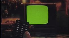 Channel Surfing TV Green Screen Remote Control Retro Television Zoom In. Remote control changing channels on an old vintage green screen television, zoom in.
