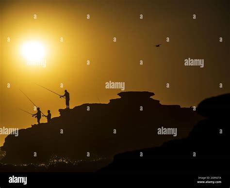 The silhouettes of fishermen at the shore during sunset Stock Photo - Alamy