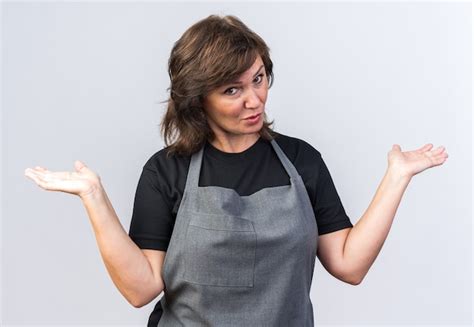 Verwirrter erwachsener weiblicher Friseur in Uniform, der die Hände ...