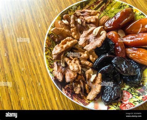 Walnuts, dates and prunes are arranged on a decorative plate, offering ...