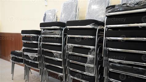 a stack of several chairs vertically leaning against a wall. The chairs ...