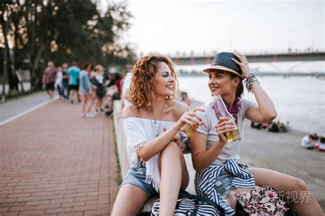 夏日的乐趣。 女孩们在城里的河边喝酒。照片-正版商用图片16xhks-摄图新视界