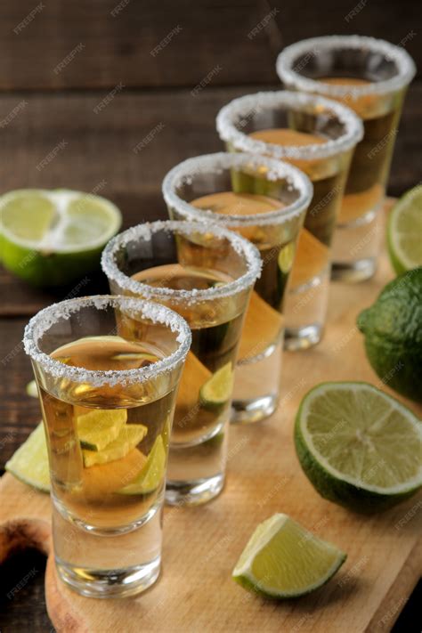 Tequila de oro en un vaso de chupito con sal y limón sobre un fondo de ...