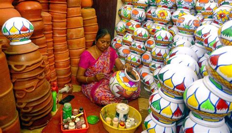 A woman decorates earthenware pots with vibrant designs