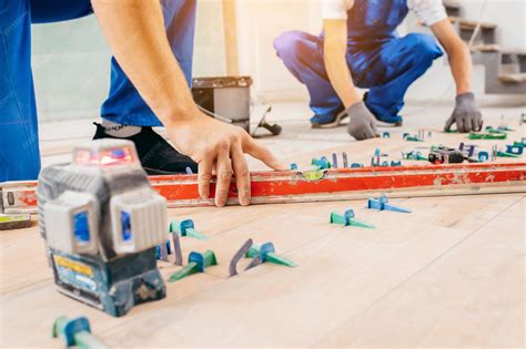 Premium Photo | Two workers in a special uniform laying tiles with tile ...