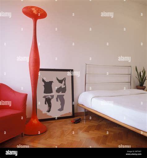 Low single bed next to modern red floor lamp Stock Photo - Alamy