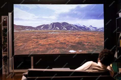 Man lounged on couch watching travel documentary with beautiful ...