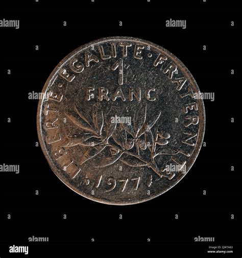 A closeup of a 1 franc coin from 1977 isolated on a black background, the former French national ...