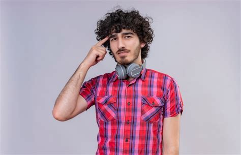 A thinking handsome man with curly hair in checked shirt in headphones ...
