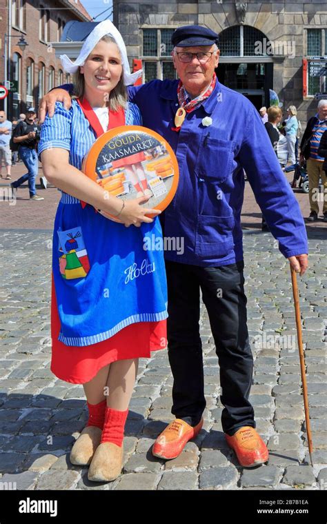 Girl in traditional Dutch attire holding a Gouda cheese ball and a ...