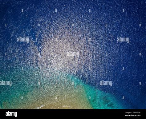 Top down aerial view of blue water and a tropical coral reef in a warm ...