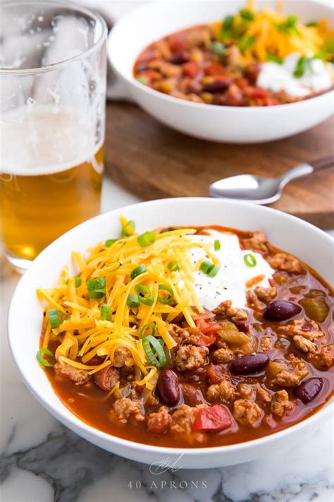 A bowl of Laura's quick slow cooker turkey chili, topped with shredded cheese, sliced green onions,