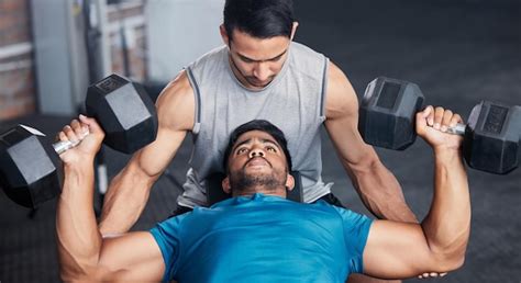 Fitness personal trainer and workout bench in gym with dumbbell for ...