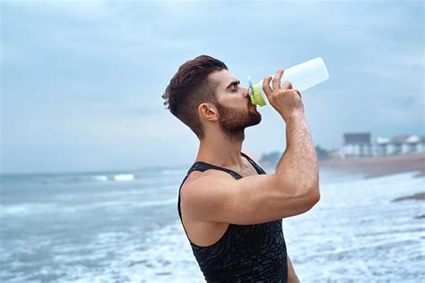 海边沙滩上喝水的帅哥侧面摄影图片 - 三原图库