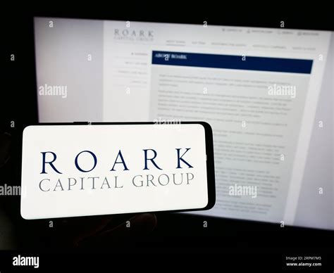 Person holding mobile phone with logo of American company Roark Capital ...