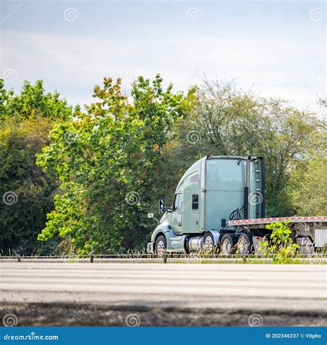 Light Green Big Rig Long Hauler Semi Truck with Flat Bed Semi Trailer Running on the Summer ...