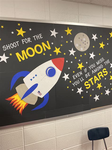 a classroom wall decorated with stars and a rocket ship on it's side ...