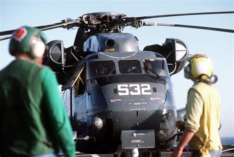 Flight deck crewmen stand by after an RH-53D Sea Stallion helicopter ...