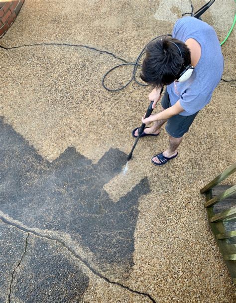 Overhead of a young GenZ adult man doing house chores power washing the ...