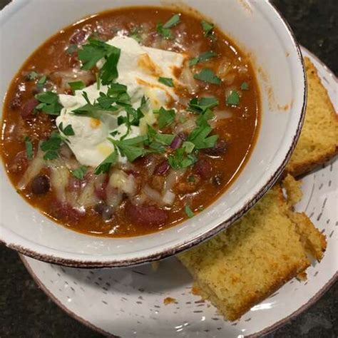 A bowl of Laura's quick slow cooker turkey chili, topped with shredded cheese, sliced green onions,