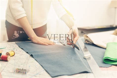 裁缝车间-女裁缝用剪刀裁剪布料照片摄影图片_ID:140994681-Veer图库
