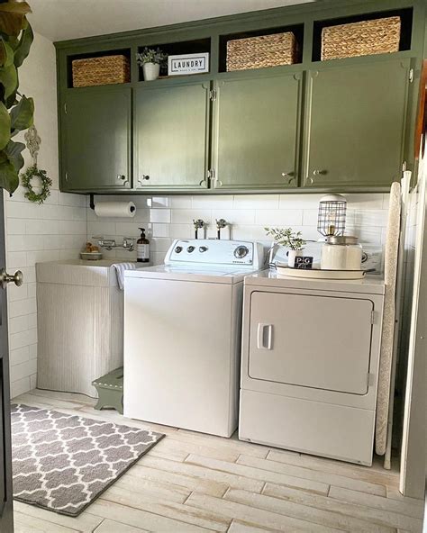 Olive green cabinets hang on a white shiplap laundry room wall. The ...