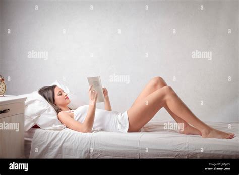 Woman reading in The Ritz-Carlton bed at a hotel