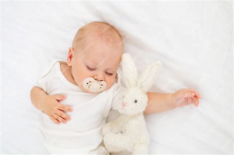 Premium Photo | Cute little newborn baby sleeping with a pacifier in his mouth under a blanket ...