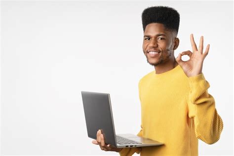 Young african american man working using laptop standing over white ...