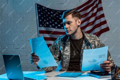 Handsome soldier holding charts and graphs while sitting in office ...