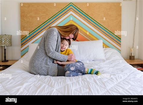 Mother and daughter cuddling on a bed in a kids room