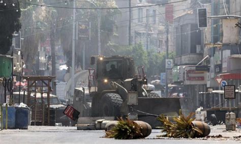 People watch an Israeli army bulldozer demolishing homes in the Palestinian urban refugee camp of Nu