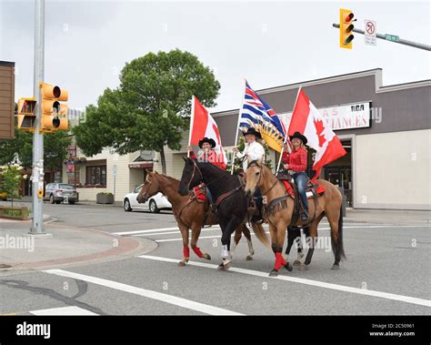 Riders carrying Canadian and British Columbia flags ride their horses ...