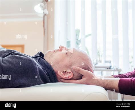 Male patient receiving cranial sacral therapy, lying on the massage ...
